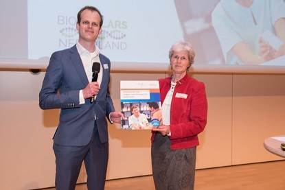 Ziekenhuisapotheker en voorzitter van het Jong CBG Thijs Giezen overhandigt het eerste exemplaar van de folder 'Antwoorden op vragen over biologische medicijnen' aan Pauline Evers van de Nederlandse Federatie Kankerpatiëntenorganisaties.